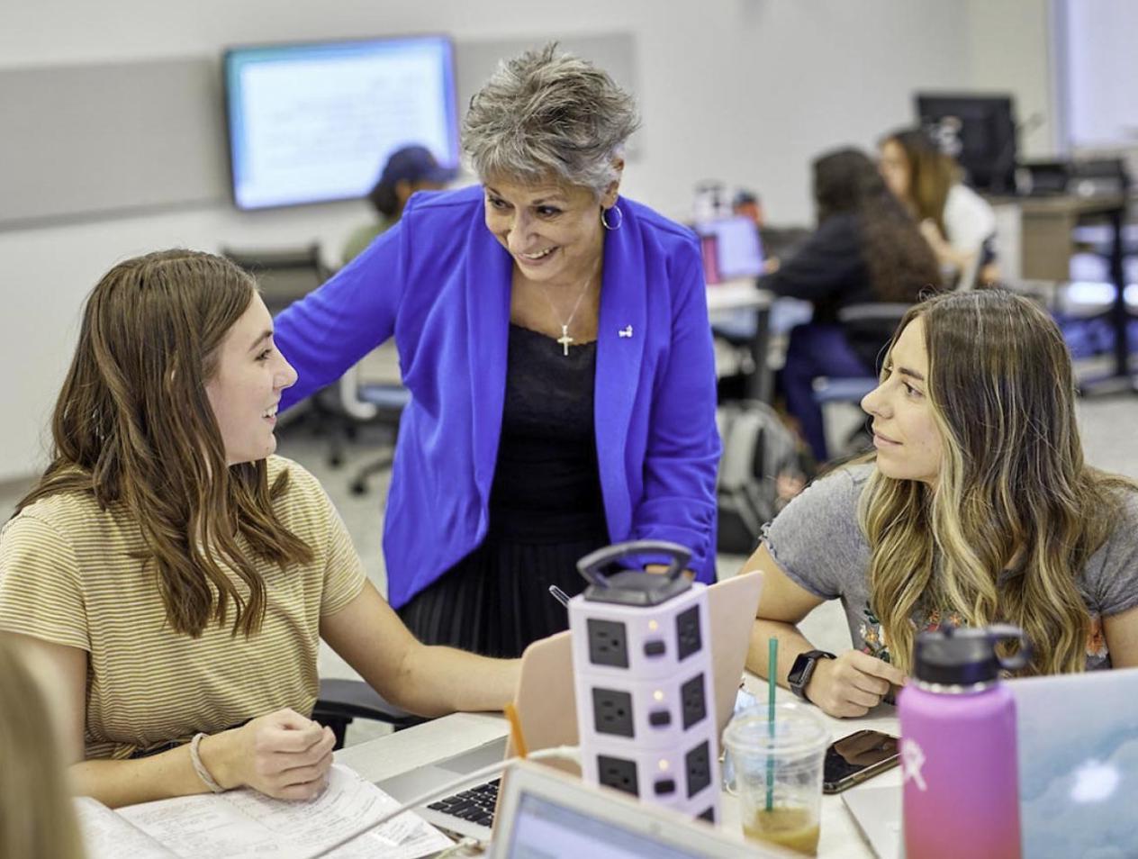 Smiling students working with professor 